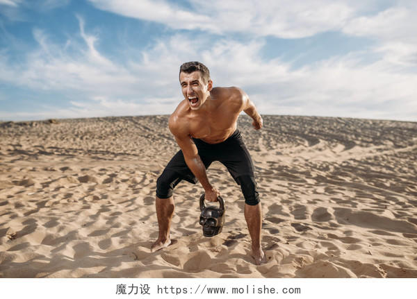 男性运动员在沙漠中做举重运动